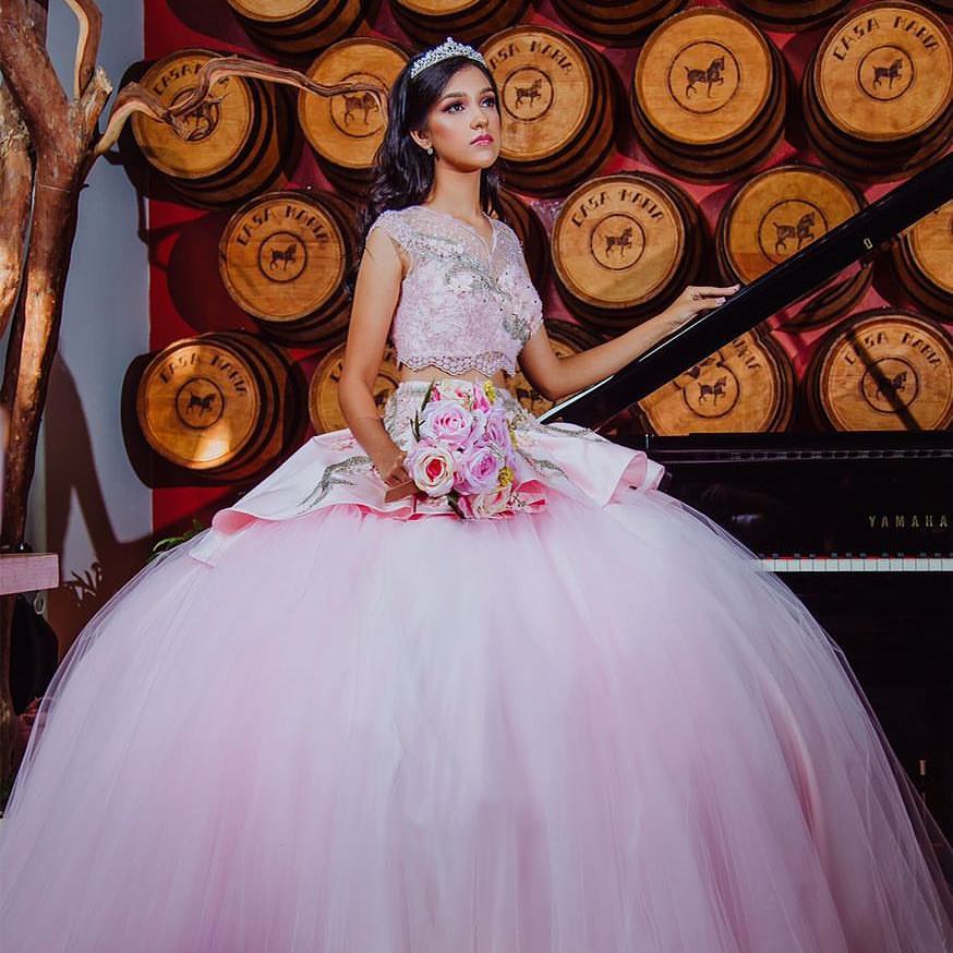 A woman in a Quinceanera gown sitting on a piano