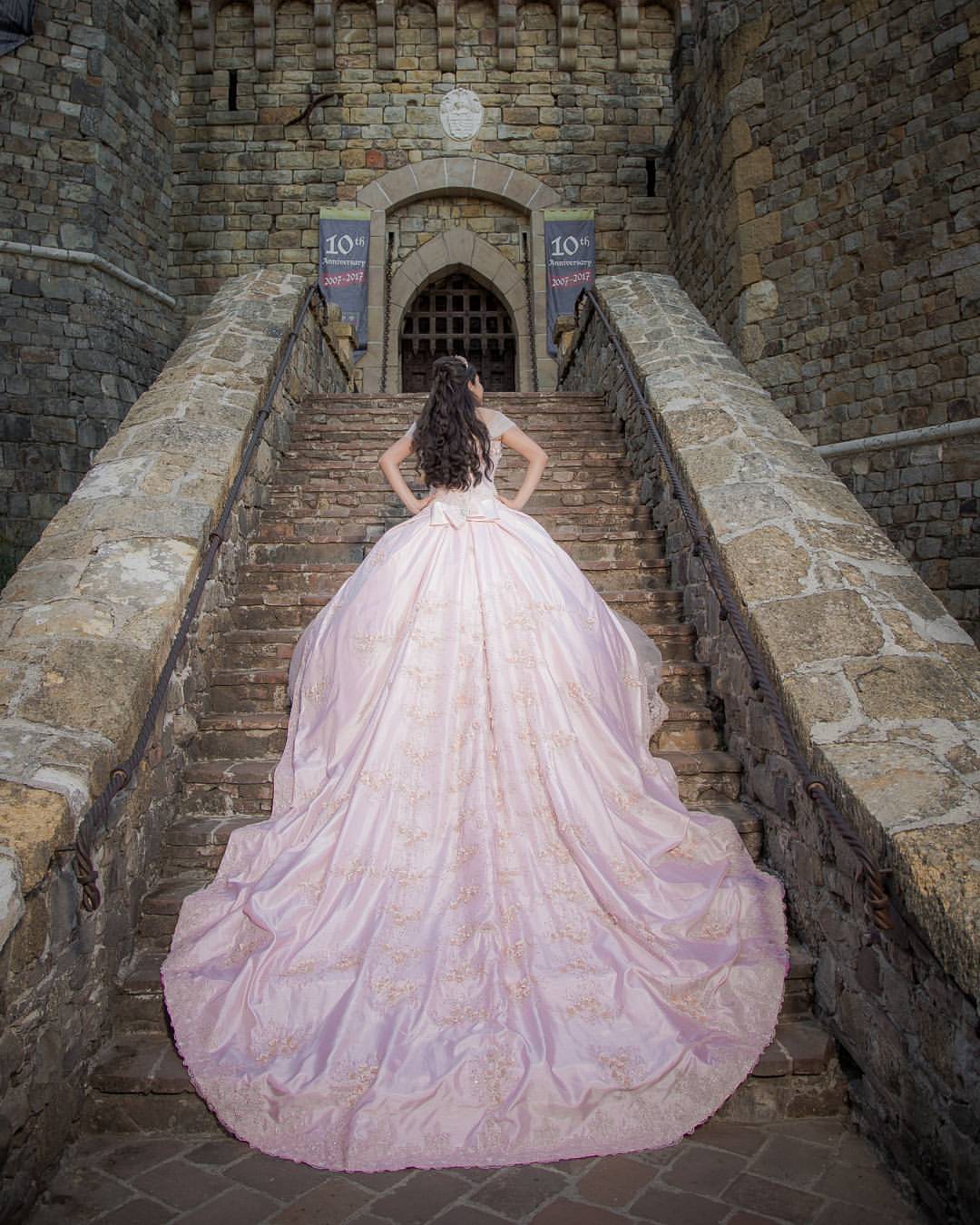A woman in a pink Quinceanera dress is walking up some stairs