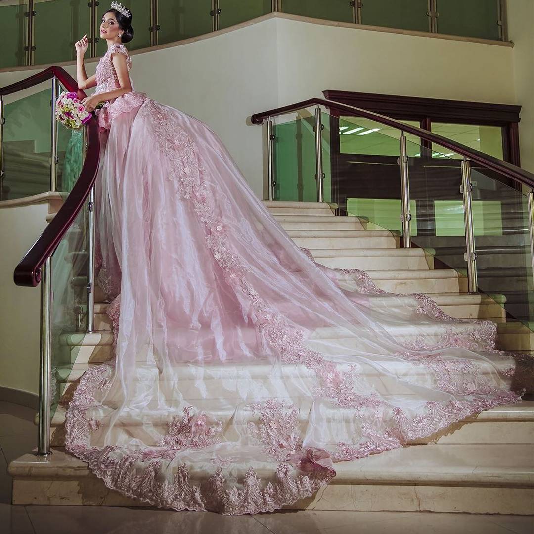 Dramatic Quinceanera dresses, a woman in a pink Quinceanera dress standing on a set of stairs