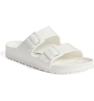 A pair of white sandals for a Quinceanera, placed on a white background outdoors.