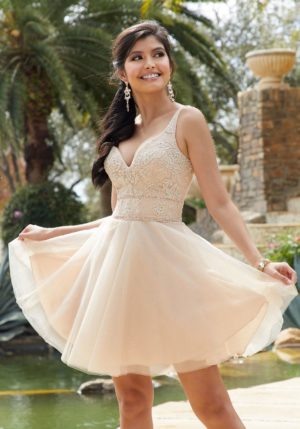 A woman in a short dress posing for a picture wearing gold Quinceañera dresses designed for Quinceanera