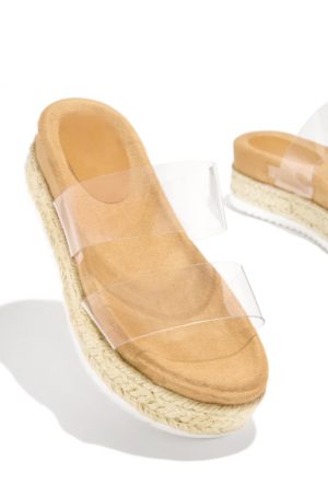 A pair of clear slippers sitting on top of a white surface in an outdoor Quinceanera setting.
