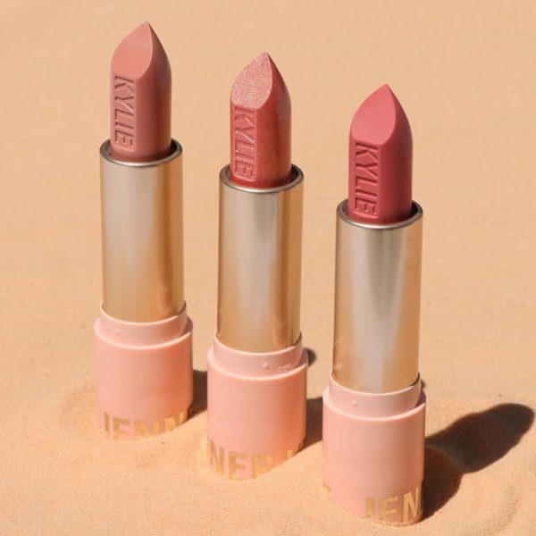A couple of Quinceanera-inspired lipsticks by Kylie Cosmetics, placed on a sandy surface