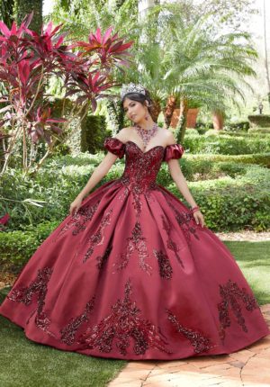 A woman wearing a red Quinceanera ball gown in a garden