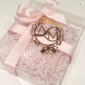 A Quinceanera Ceremony Supply box with a pink ribbon and a monogram on it