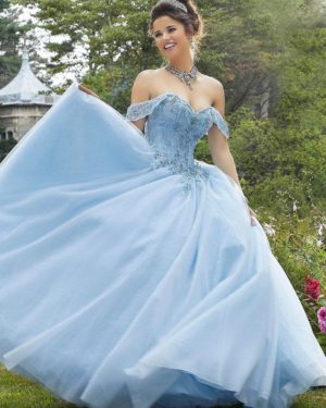 A woman wearing a blue dress from the Morilee Valencia Quinceanera collection, standing in a garden