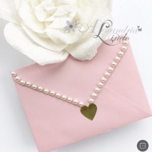 Quinceanera accessories including a chain jewellery, a pink envelope with a pearl necklace, and a rose
