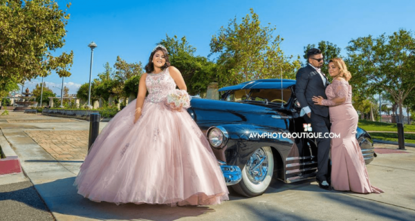 A Quinceanera in a beautiful wedding dress standing next to a vintage car