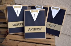 A cobalt blue Chamberlain holding a couple of cards with a bow tie on them during a Quinceanera celebration.