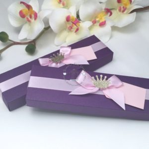 A Quinceanera image featuring a lilac floral design, a purple box with a pink ribbon, and a crown on it.
