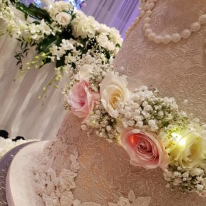A close up of a Quinceanera floral design and wedding cake on a table.