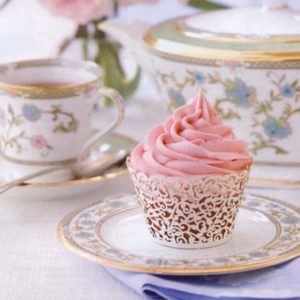 A Quinceanera cupcake sitting on top of a white plate with lace wrappers
