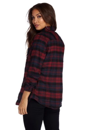 A woman wearing a plaid jacket and a red and black plaid shirt at a Quinceanera celebration.