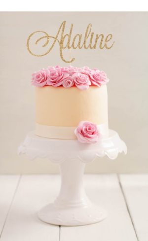 A white Quinceanera cake with a pink rose cake topper on top
