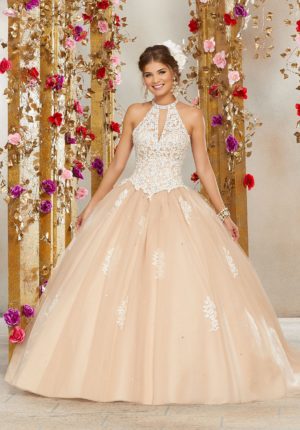 A woman wearing the Morilee 60075 Quinceanera gown, standing gracefully in front of a beautiful backdrop of flowers