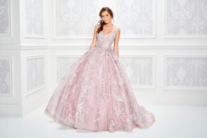 A woman in a pink Quinceañera gown standing in a white room