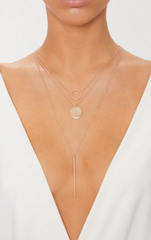 A woman wearing a white dress and a gold necklace with a plunging neckline at a Quinceanera celebration.