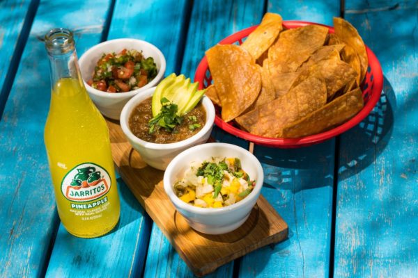 A table topped with bowls of Mexican cuisine next to a bottle of beer, perfect for a Quinceanera celebration.