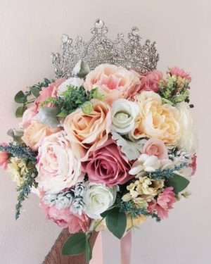 A Quinceanera floral design featuring a flower bouquet with a tia on top of it