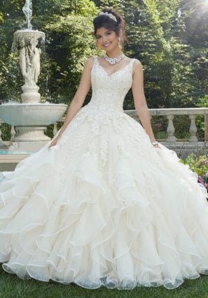 A woman in a lace Quinceanera dress standing in front of a fountain