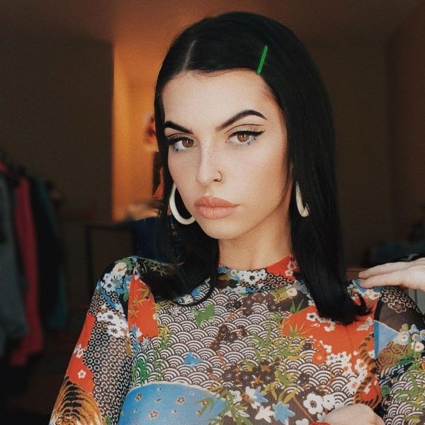 A beautiful woman with black hair wearing a colorful top, representing Quinceanera beauty and fashion.