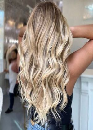 Quinceanera: A woman with long blonde hair in a salon getting hair extensions with blonde highlights