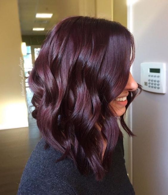 A woman with dark burgundy hair color wearing a dark sweater