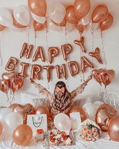 A simple and easy Quinceanera decoration at home featuring a woman sitting on a bed surrounded by balloons