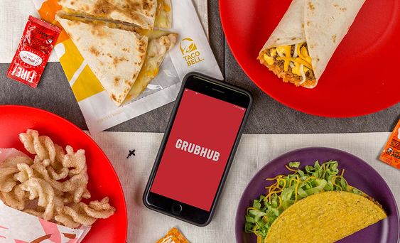 A Quinceanera celebration with a table topped with plates of food, a cell phone, and Taco delivered by Grubhub