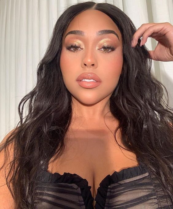 A photo of Jordyn Woods, a woman with long black hair, wearing a black bra top at a Quinceanera event