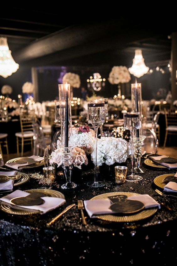 An elegant and classy Quinceanera birthday party. The table is covered with a black table cloth and adorned with gold place settings.
