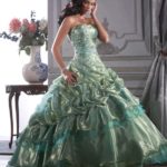 A woman in a green dress posing for a picture in a Quinceanera dress inspired by Disney princesses